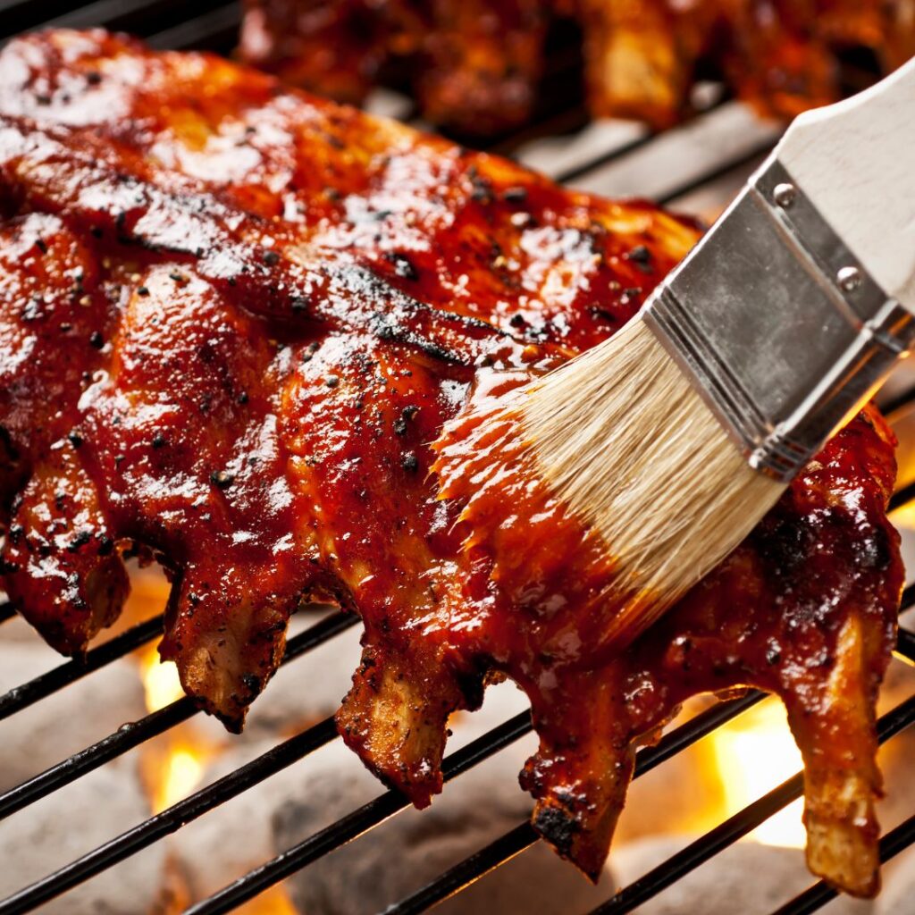 Ribs being brushed with BBQ sauce